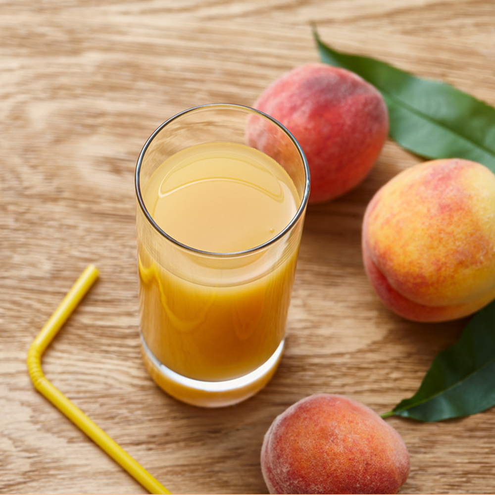 Glass of fresh peach juice and ripe fruits